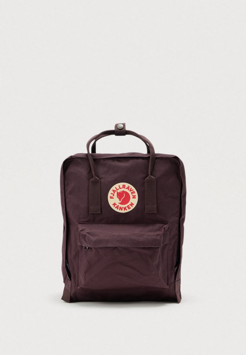 Bordowy plecak z poliestru z wyraźnym okrągłym logo, górnym uchwytem i przednią kieszenią na zamek. Prostokątny kształt z regulowanymi paskami na ramiona.