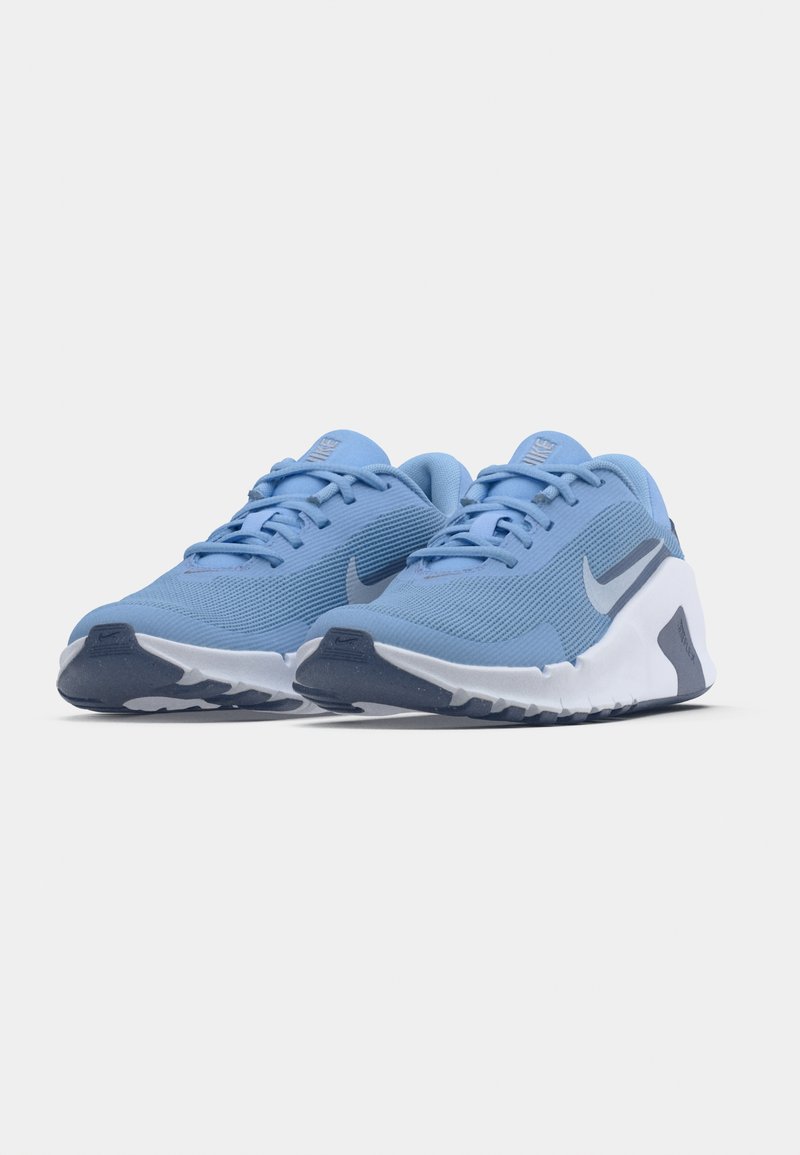 Zapatillas deportivas azul claro con parte superior texturizada, suela blanca y detalles en azul oscuro. Incluyen cordones estándar y un detalle con el logo de Nike.