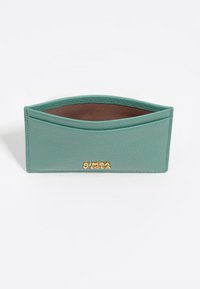 Cartera de cuero verde menta con un acabado texturizado, borde superior curvado y acentos dorados en el logo. El interior presenta un forro marrón en contraste.