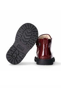Bordeaux gepatineerde leren enkellaarsjes met een zwarte rubberen zool, met een gestructureerde loop voor grip en een sluiting met een zijknop.