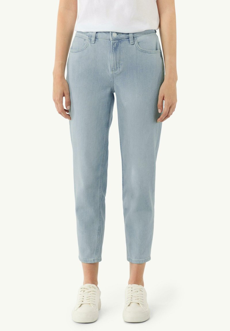 Jasnoniebieskie dżinsy o slim fit, z pięcioma kieszeniami, zapięciem na guzik i mankietami. W połączeniu z białymi trampkami.