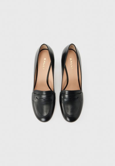 Paire de mocassins pour femmes en cuir noir avec bouts arrondis et bride décorative, vue de dessus sur un fond clair.