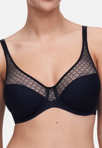 Marineblauwe bh met een zachte stoffen basis en een doorschijnende mesh overlay met een ruitpatroon. Ondersteuning door beugels en verstelbare bandjes.