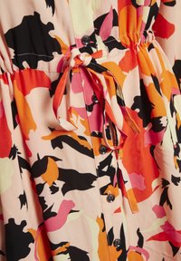 Bloemenjurk van lichtgewicht stof; voorzien van abstracte patronen in perzik, roze, oranje en zwart. Inclusief een trekkoord in de taille en knoopdetails.
