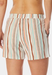 Pruhované krátké kalhoty s elastickým pasem, vyrobené z měkkého materiálu. Barvy zahrnují hnědou, mátovou, korálovou a krémovou.