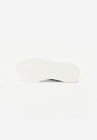 Suela de zapato de material de goma blanca, con un patrón texturizado que presenta estrías y formas geométricas para tracción y estabilidad.