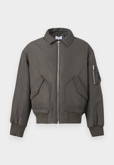 Veste bomber vert foncé avec fermeture éclair à l'avant, deux grandes poches à rabat inclinées, poignets et ourlet côtelés, et une poche zippée sur la manche gauche.