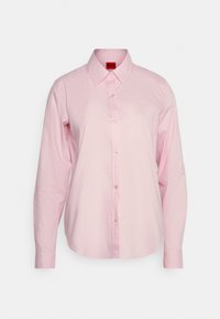 Jasnoróżowa, długosleeve'owa koszula z guzikami, wykonana z bawełny, z ko�łnierzykiem w kształcie szpilki, pojedynczym logo na piersi i zaokrąglonym dołem. Gładka tekstura.