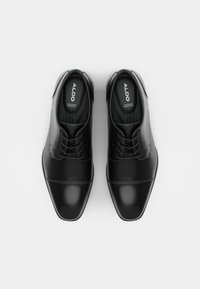 Chaussures habillées en cuir noir à finition lisse, dotées d'un bout arrondi, d'un laçage et de détails de couture subtils sur la partie supérieure.