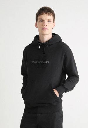 Sudadera con capucha negra hecha de tejido suave, con un bolsillo frontal, capucha con cordón y el logotipo bordado de "Calvin Klein Jeans".