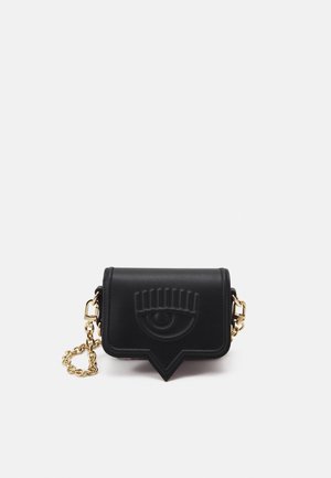 Czarna skórzana kopertówka z tłoczonym motywem oka na klapie i złotym łańcuszkiem na jednolitym białym tle.