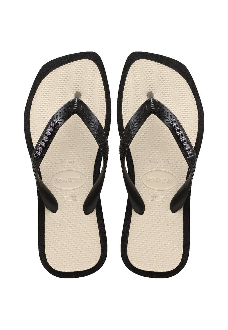 Svart gummiflip-flops med teksturerte stropper, solid såle, og beige fotbed med preget logo og størrelsesdetaljer.