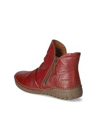 Stivale alla caviglia in pelle rossa con zip, punta rotonda e superficie testurizzata. Presenta cuciture a contrasto e una suola beige flessibile.