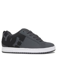 Grå sneakers lavet af syntetisk materiale med en glat tekstur, der har sorte accenter, snørebånd og en hvid sål. Bemærkelsesværdigt logo på siden.