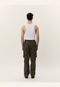 Un top alb fără mâneci și pantaloni cargo de culoare verde închis cu un model de camuflaj texturat, având buzunare laterale și o croială lejeră, văzuți din spate.