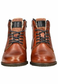 Botas de cuero marrón con un acabado suave, que presentan cordones oscuros, un cuello acolchado y una suela de goma. Costuras decorativas a lo largo de la parte superior.