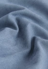 Blaues Wildleder mit einer weichen, strukturierten Oberfläche, die sanfte Falten und eine einheitliche Farbe aufweist und somit das glatte Gefühl und die Tiefe betont.
