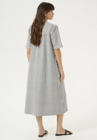 Juostuota, iki kulkšnių siekianti suknelė su trumpomis rankovėmis, laisvo kirpimo, su mygtuko detale nugaroje ir pagaminta iš lengvos medžiagos.