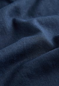 Dark blue fabric with visible woven texture and soft folds creating gentle shadows and highlights.