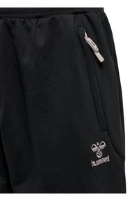 Pantaloni da jogging neri realizzati in un morbido tessuto, con una tasca laterale con una cerniera grigia e un logo ricamato sulla gamba sinistra.