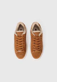 Brown suede sneakers with a white rubber sole, featuring a plush cream-colored lining and laces. Logo displayed on the side.