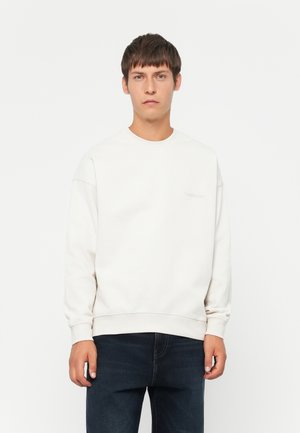 Lys beige sweatshirt med rund hals, ribbede mansjetter og nederkant. Har en subtil logo-detalj på forsiden. Børes med mørke jeans.
