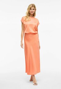 Robe maxi en satin pêche avec des manches courtes et une coupe loose. Texture lisse, design long jusqu'au sol, présentant une silhouette simple et sans motifs.