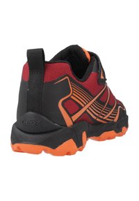 Zapatilla deportiva negra y roja con detalles en naranja, parte superior de tela texturizada y suela de caucho resistente con patrones de tracción pronunciados.