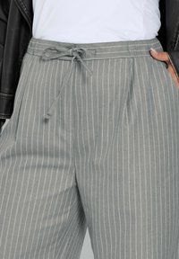 Grårandiga byxor i ett lätt material med dragsko i midjan och sidofickor. Vertikala ränder förstärker designen.