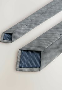Blaue gemusterte Krawatten mit einer strukturierten grauen Außenlage und einem glatten blauen gepunkteten Innenfutter, mit schräg geschnittenen Enden.