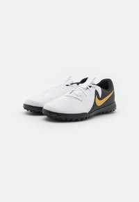 Weiße Sportschuhe mit einer strukturierten Oberfläche, schwarzer Gummisohle und einem goldenen Nike-Logo an der Seite. Mit grauen und schwarzen Akzenten.