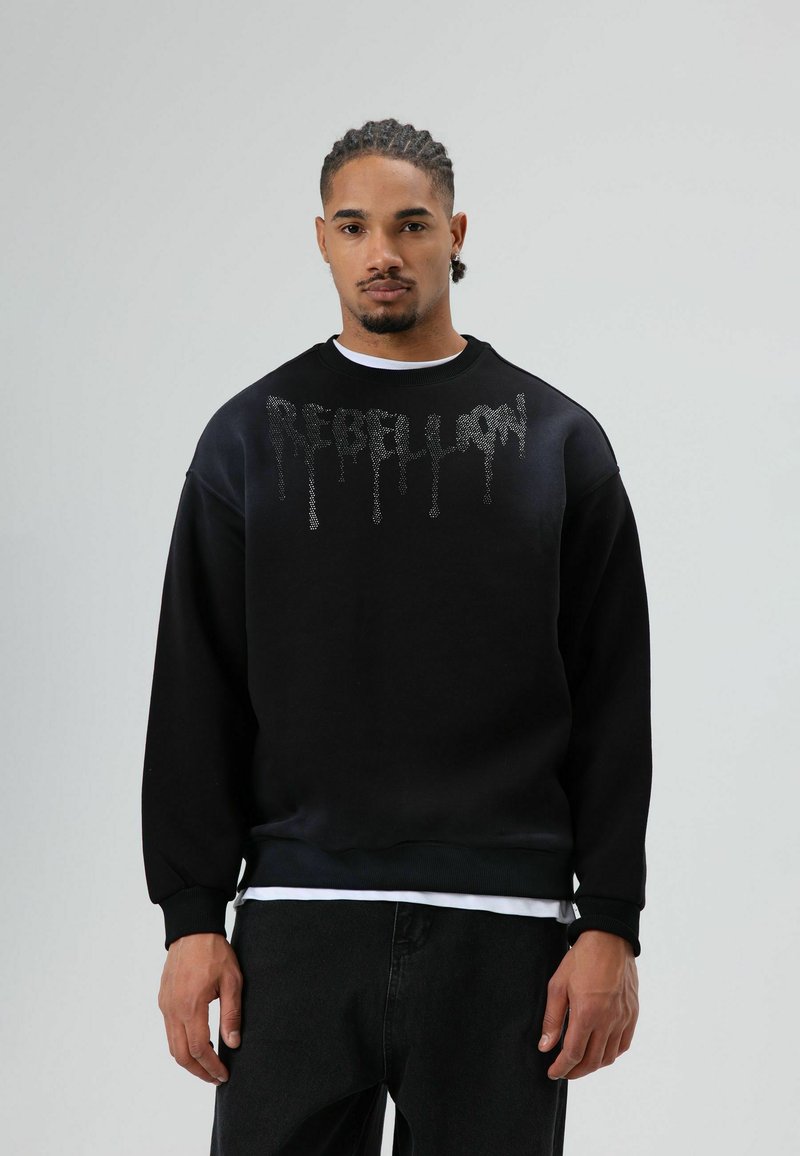 Zwarte sweatshirt met een gestructureerde "REBELLION" print in een druppelend ontwerp. Voorzien van een ronde hals en geribbelde manchetten, gecombineerd met donkere jeans.