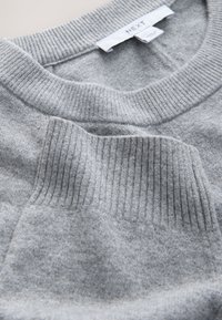 Gray knitted sweater with a ribbed crew neckline, featuring a textured patch pocket on the front and smooth fabric throughout.