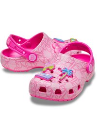 Zuecos rosas tipo slip-on con correas en el talón, decorados con un árbol de palmera, patines y charms en forma de corazón, que presentan un diseño de patrón en letras.