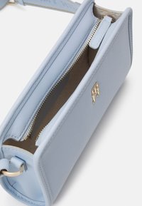 Borsa a tracolla in pelle blu chiaro dal design rettangolare, con chiusura a zip, accessori in oro e un interno marrone testurizzato. Presenta un accento con logo.