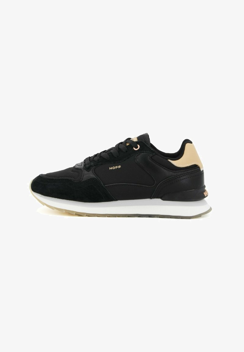 Zapatillas negras que combinan materiales de ante y cuero, con un acento beige en el talón, logo dorado y una suela intermedia blanca.
