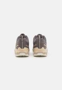 Grå och beige Salomon-skor med övre del i texturerad mesh, förstärkt häl och gummisulor, med minimal märkning på baksidan.