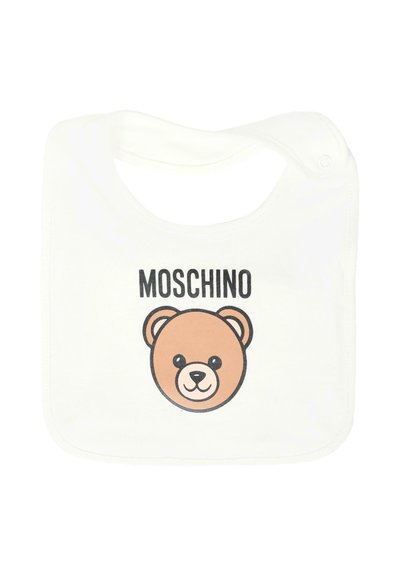 Bawełniany śliniak w białym kolorze z okrągłym wzorem misia w jasnobrązowym kolorze z czarnymi akcentami; nad grafiką umieszczona jest nazwa marki "MOSCHINO".