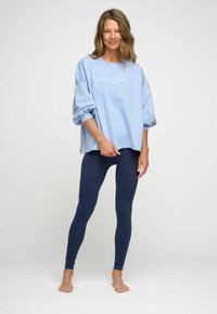 Lichtblauwe oversized sweatshirt met de tekst "vind je balans", gecombineerd met marineblauwe legging. Zachte stof, relaxte pasvorm en enkel lengte.