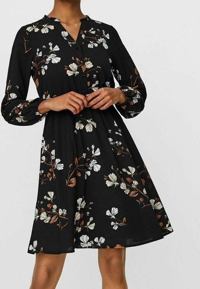 Musta kukallinen mekko pitkillä hihoilla, jossa on nappisulku, valkoisia ja ruskeita kukkakuvioita sekä virtaava A-linjainen siluetti.