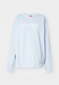 Sudadera azul claro con cuello redondo, mangas largas y puños de canalé. Presenta letras blancas en relieve "HUGO" en la parte frontal.