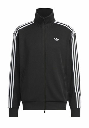Veste de survêtement Adidas noire avec trois bandes blanches sur les manches, fermeture éclair intégrale à l’avant, col montant et logo trèfle Adidas sur la poitrine gauche.
