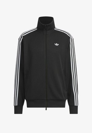 Veste de survêtement Adidas noire avec trois bandes blanches sur les manches, fermeture éclair intégrale à l’avant, col montant et logo trèfle Adidas sur la poitrine gauche.