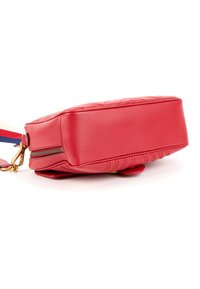 Sac bandoulière rectangulaire rouge en cuir matelassé, fermeture éclair dorée et bandoulière réglable rayée rouge, blanche et bleue sur fond blanc.