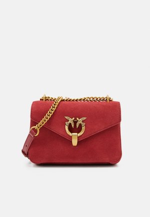 Red suede handbag with a gold chain strap, featuring a decorative clasp with two bird accents and a flap closure.