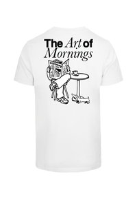 Weißes T-Shirt mit einem schwarzen Grafikbild einer sitzenden Person, die eine Zeitung liest, und einem Hund neben einem Tisch mit einer Kaffeetasse. Darüber steht der Text "Die Kunst der Morgen".