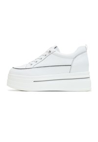 Sneaker en cuir blanc avec une semelle épaisse, doté d'un système de laçage et d'une ligne d'accent grise sur le côté. Texture lisse, design minimaliste.