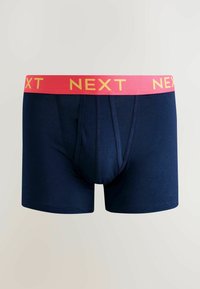 Tmavě modré bavlněné boxerky s růžovým páskem se žlutým nápisem "NEXT". Design zahrnuje těsný střih a hladkou texturu.