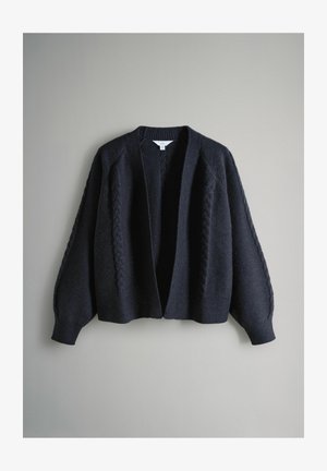 Tmavomodrý pletený sveter s reliéfnym vzorom vrkoča, otvorený vpredu a s rukávmi s klesajúcimi ramenami. Vyrobený z mäkkej, hrubej priadze pre teplo.