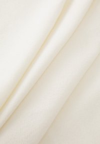 Tissu blanc texturé plié en couches, affichant une surface douce et lisse avec un motif diagonal subtil.